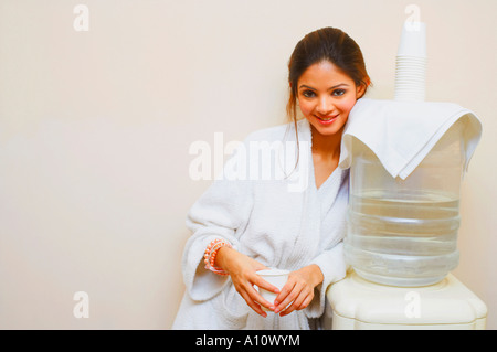 Portrait of a young woman leaning against a water cooler Stock Photo