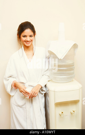 Portrait of a young woman leaning against a water cooler Stock Photo