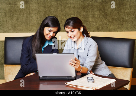 Two businesswomen sitting in an office and using a laptop Stock Photo