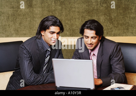 Two businessmen sitting in an office and using a laptop Stock Photo