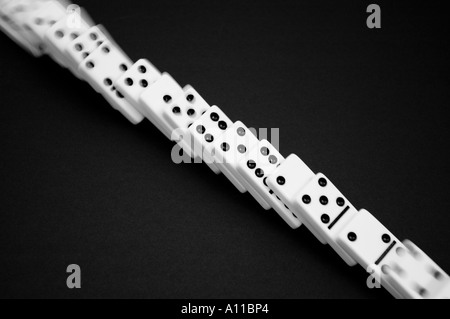 Dominos in a row toppling on a black background Stock Photo