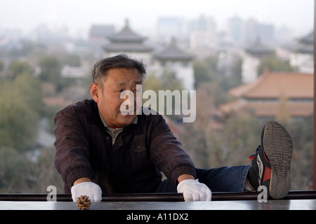 Senior stretches out in Jingshan Park, overlooking the Forbidden City, Beijing China Stock Photo