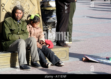 Homeless man and his young daughter on a sidewalk in Beijing, China Stock Photo