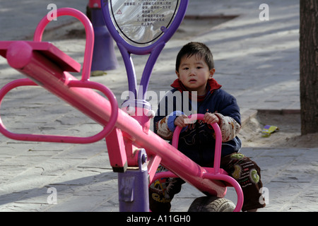 Chinese one child policy leaves this boy alone on a Playground teeter totter, Dongdan Park, Beijing,   China Stock Photo