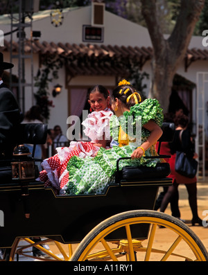 Jerez Horse Fair, Feria del Caballo, young girls riding carriage dressed in trajes de gitanas (gypsy dresses), Jerez de la Frontera, Andalusia, Spain Stock Photo