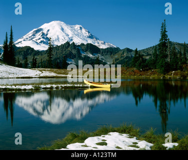 Yellow canoe rests on bank of small mountain tarn in Mount Ranier National Park in Washington Stock Photo