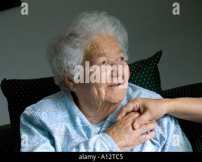 Holding elderly lady hands contented cared for senior old age pensioner elderly lady woman holds comforting hand of carer nurse secure in her day room Stock Photo
