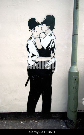 A piece of stencil sprayed graffiti of two kissing Gay Policemen by Banksy sprayed on a wall in Brighton, Sussex. Stock Photo