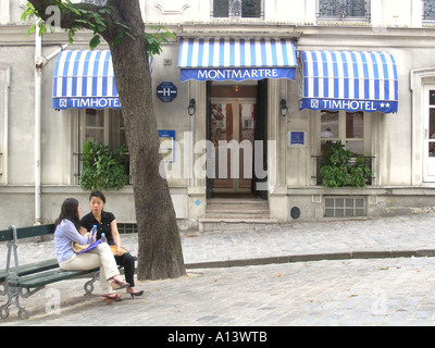 two Asian ladies relaxing on bench in front of Parisian hotel France Stock Photo