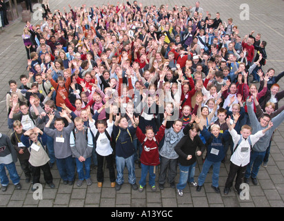 a party of primary school children looking up at camera and waving Stock Photo