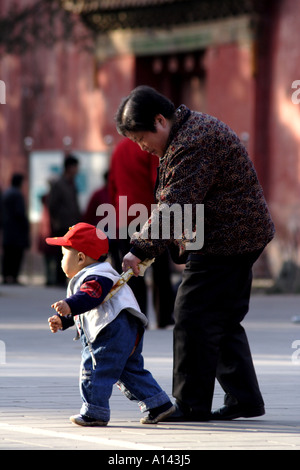 Grandson walks with the help of Grandmother in Jingshan Park, Beijing, China Stock Photo