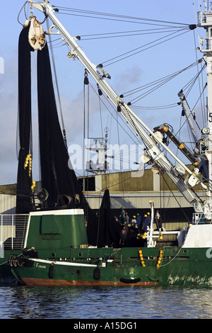 Tuna trawler alongside processing plant loading nets prior to putting to sea Victoria Mahe Seychelles Stock Photo