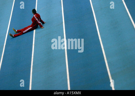 lone athlete sitting on the track of a indoor competition awiting to be called for her event Stock Photo