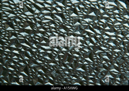 Horizontal abstract close up of rain drops on a piece of patterned glass. Stock Photo