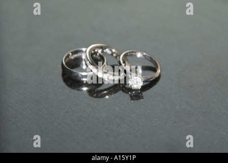 Horizontal close up of the Bride and Groom's platinum wedding bands and bride's diamond engagement ring on a black background. Stock Photo