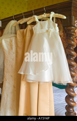 Vertical close up of the bridal gown, bridesmaids and flowergirls dresses hanging up being aired just before a wedding. Stock Photo