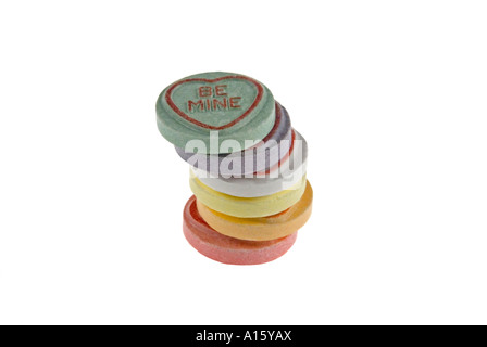 Horizontal close up of a pile of colourful loveheart sweets arranged in a stack on a white background. Stock Photo