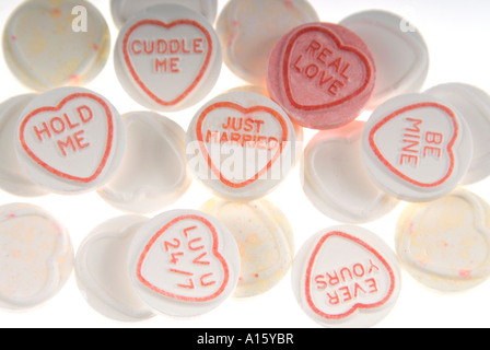 Horizontal elevated close up of a pile of white loveheart sweets with one red 'real love' loveheart on a white background. Stock Photo
