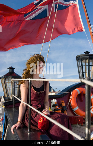 Woman dressed in period costume sits at stern of the Grand Turk at the Great Yarmouth Maritime Festival Stock Photo