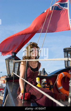 Woman dressed in period costume sits at stern of the Grand Turk sailing ship at Maritime Festival in great Yarmouth Stock Photo