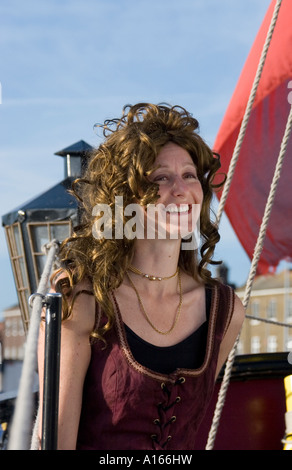 Woman dressed in period costume sits on deck of 18th century ship Stock Photo