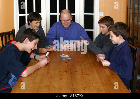 Family sat at table playing cards Stock Photo