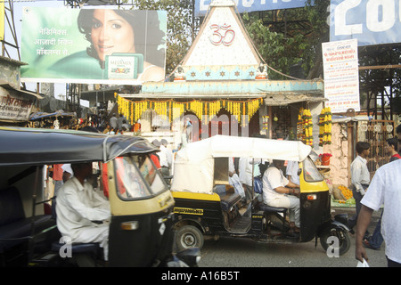 Indian street Hindu temple with OM written surrounded by modern hoardings and auto taxi at Borivali Bombay Mumbai India Stock Photo