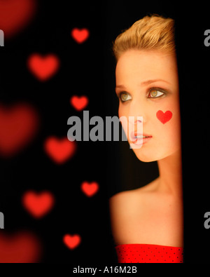 Portrait of young woman 18, 19, 20, 21, 20-24, 24-29, 30-34, years old with red heart painted on her cheek Stock Photo