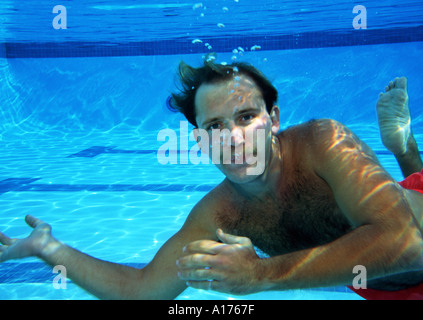 Underwater Man swimming in pool holding breath Stock Photo