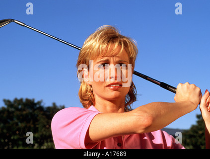 Attractive middle aged woman at peak of golf swing Stock Photo
