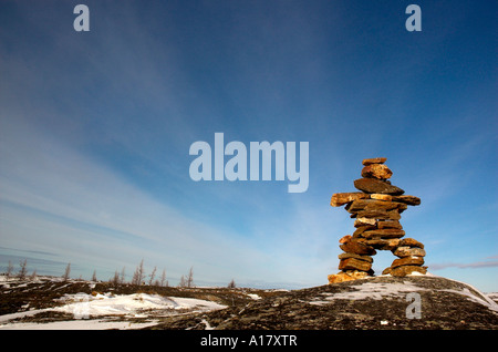 High clouds behind an inukshuk on a hill overlooking the arctic village of Kuujjuaq Stock Photo