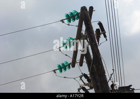 Three phase power lines with glass insulators on wooden support poles Village of Lefkes Island of Paros Greece Stock Photo