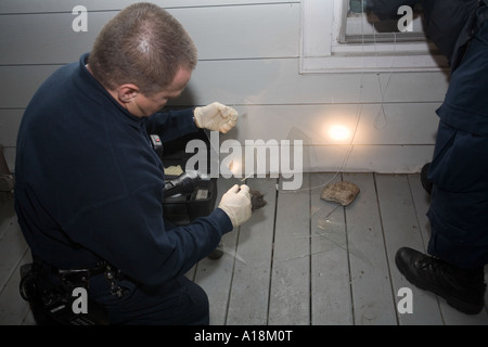 Crime Scene Technician and Detective inspects broken window at the scene of a burglary Kansas City MO Police Crime Lab Stock Photo