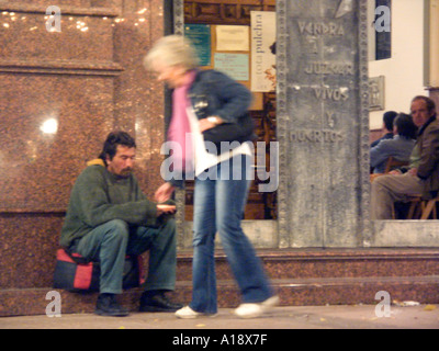 Spanish Homeless Beggar receives a money donation from a kind English lady outside a church at Christmas, homeless homelessness Stock Photo