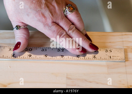 Woman age 64 measuring board for home remodeling project. St Paul Minnesota USA Stock Photo
