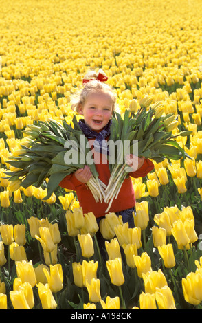 Little blond girl standing in a flowerfield Stock Photo