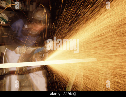 Workman in protective safety gear using a hand held disc cutting grinding machine Stock Photo