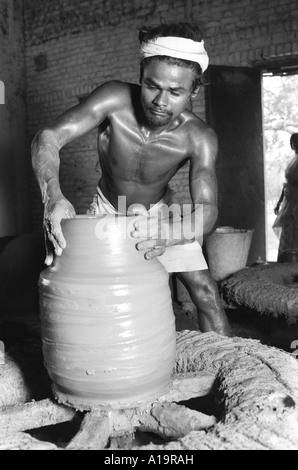 B/W of a potter turning a large pot on a primitive wheel turned by hand at a village workshop in Tamil Nadu, South India Stock Photo