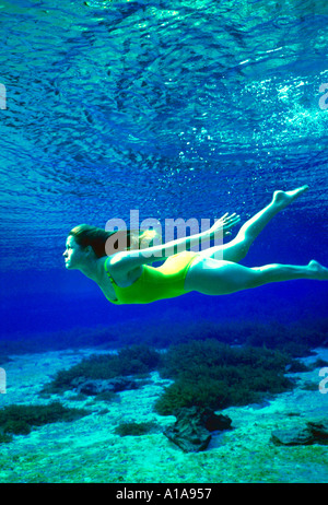 young woman swims underwater among coral Stock Photo