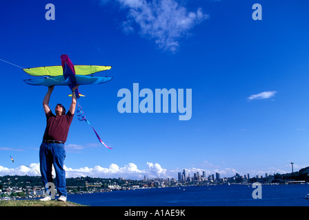USA Washington Seattle Man launches kite from top of hill at Gas Works Park on summer afternoon along Lake Union Stock Photo