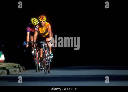 USA Washington Seattle Mens bicycle racers ride along road race course through Seward Park on summer evening Stock Photo