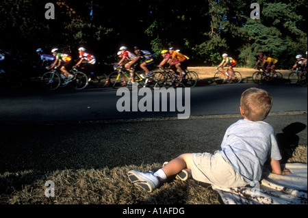 USA Washington Seattle Young boy watches mens bicycle road race through Seward Park on summer evening Stock Photo