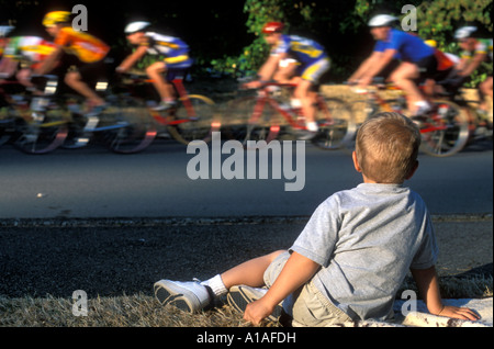 USA Washington Seattle Young boy watches mens bicycle road race through Seward Park on summer evening Stock Photo