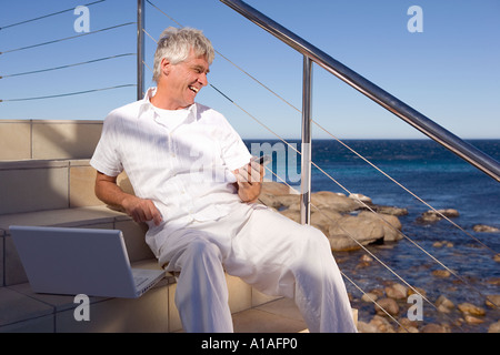 Man by the sea with laptop and mobile phone Stock Photo