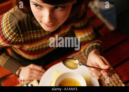 Young woman eating soup