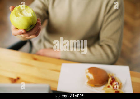Man with half eaten apple and cheeseburger Stock Photo