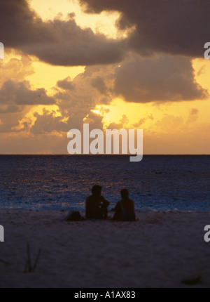 couple sitting on a beach as the sun sets on the atlantic on irelands west coast Stock Photo