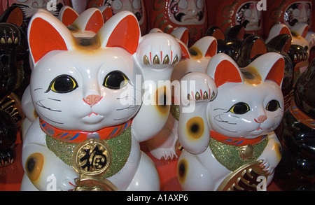 Maneki Neko Lucky Cat mascot with a raised paw as sold outside shrines and temples throughout Japan Stock Photo