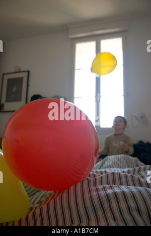 a bedroom scene with young boy in background playing with balloon in front of a bright window Stock Photo