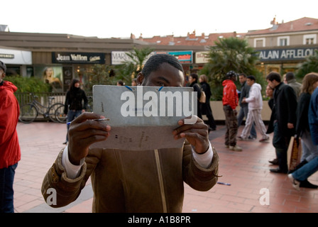 an african male street vendor holds up a clip board to hide his face for fun Stock Photo